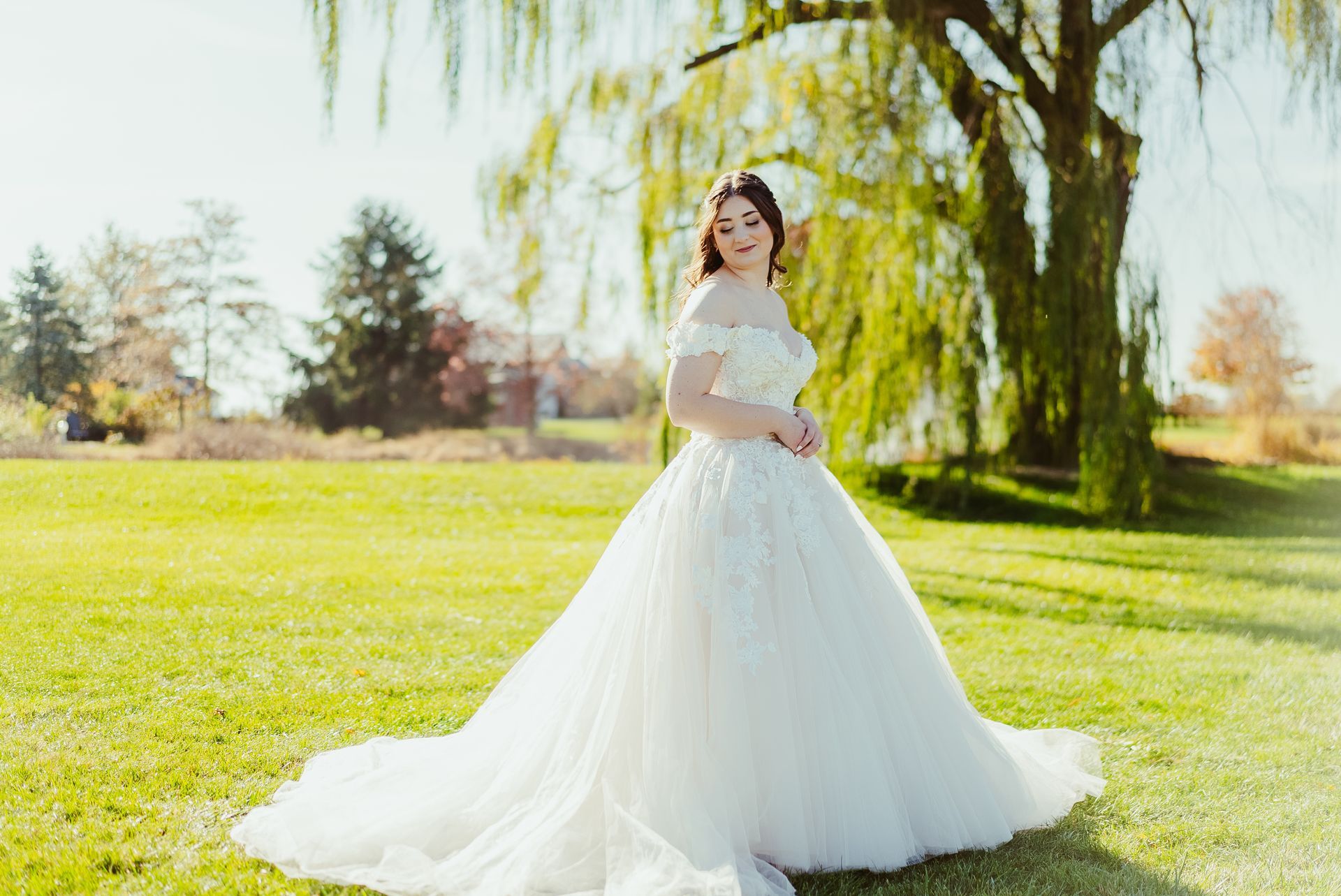A woman in a wedding dress is standing in a grassy field.
