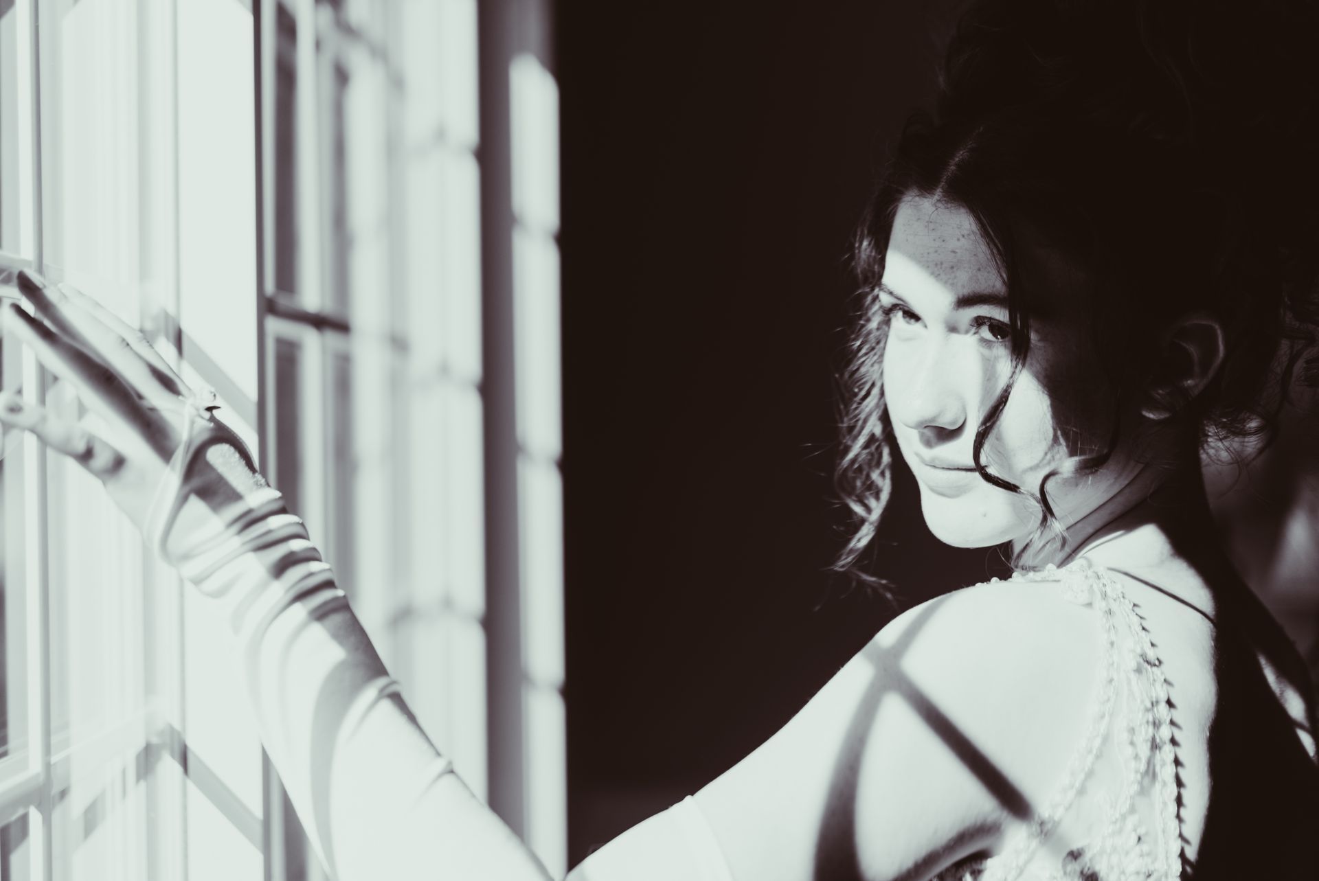 A black and white photo of a woman looking out of a window.