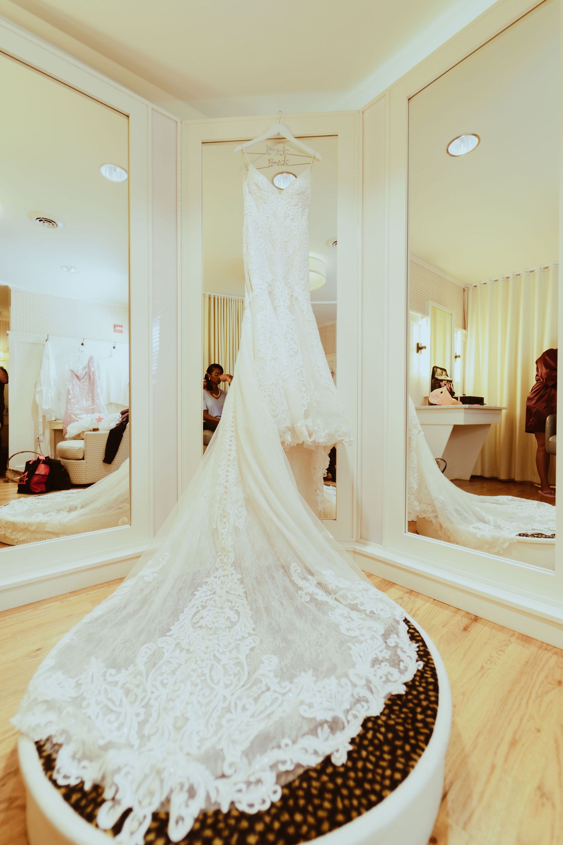 A wedding dress is hanging in front of a mirror in a room.