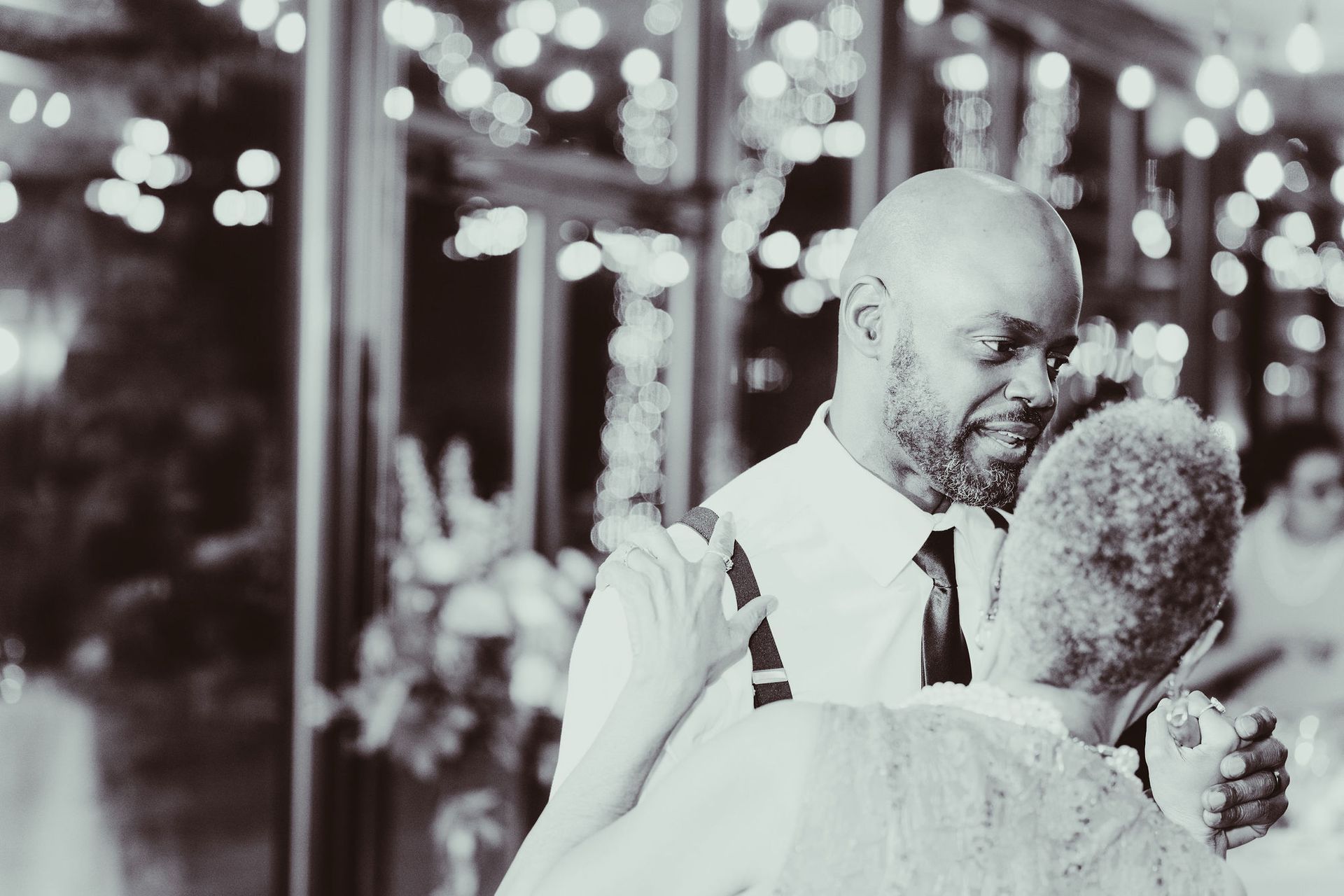A black and white photo of a man and woman dancing at a wedding reception.