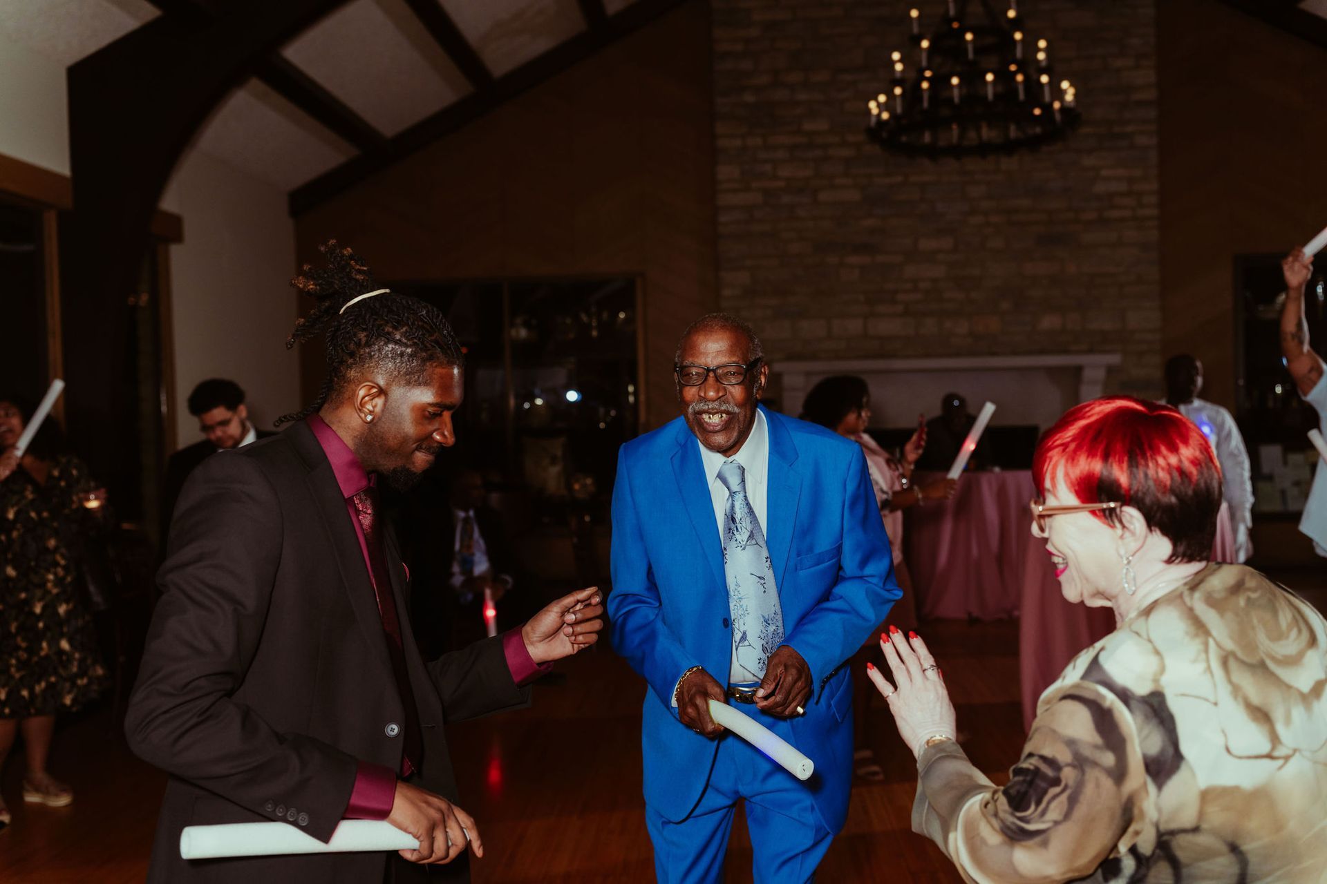 A group of people are dancing in a room at a wedding reception.