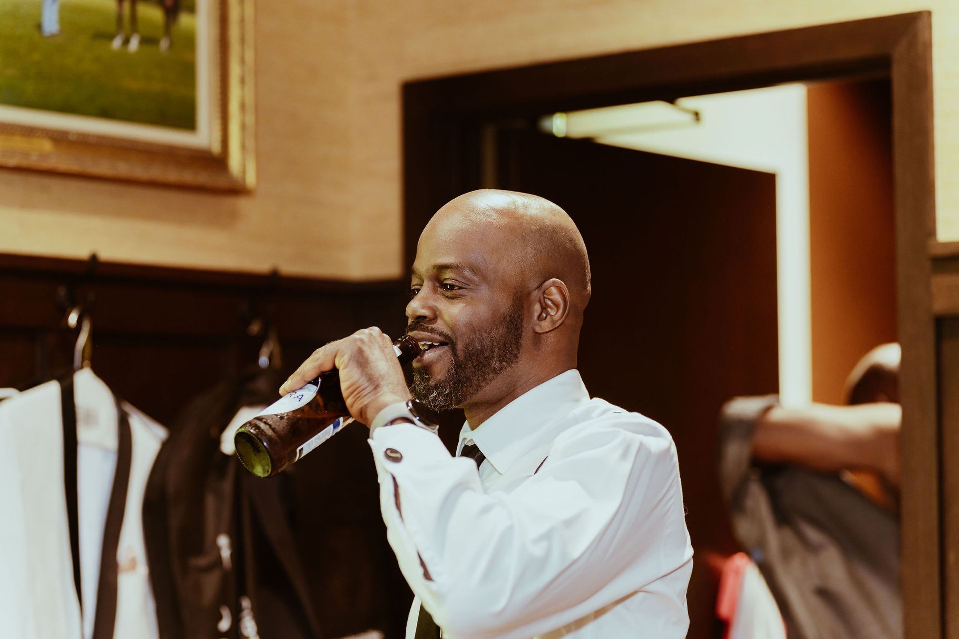 A man is drinking from a bottle in a room.