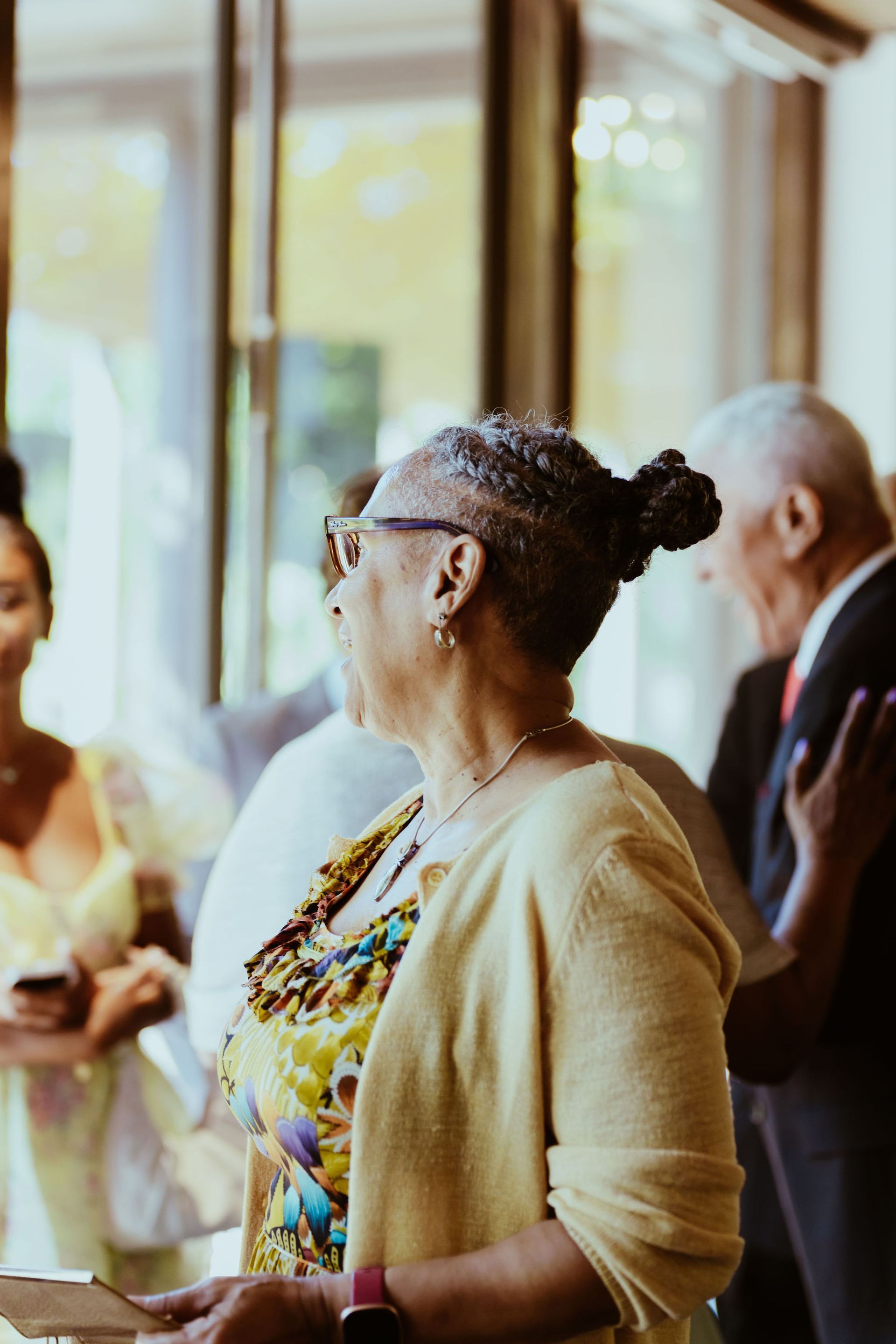 A woman in a yellow sweater is standing in front of a group of people.