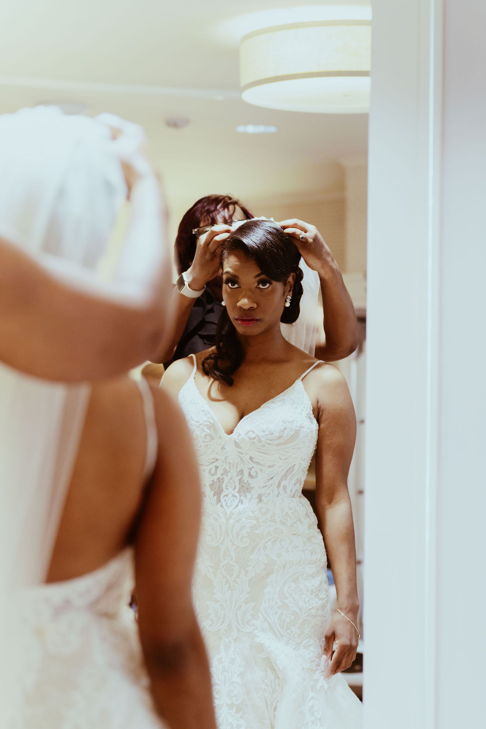 A woman in a wedding dress is looking at herself in a mirror.