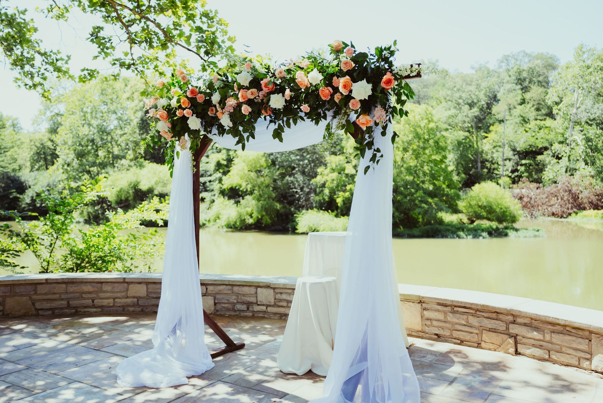 A wedding arch decorated with flowers is sitting in front of a lake.