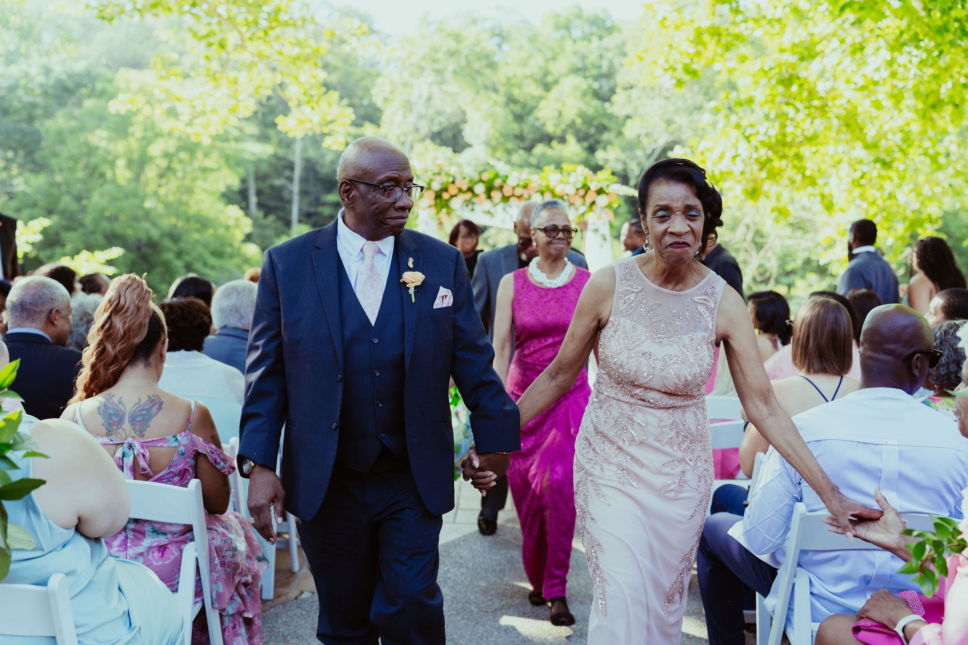 A man and woman are walking down the aisle at a wedding holding hands.