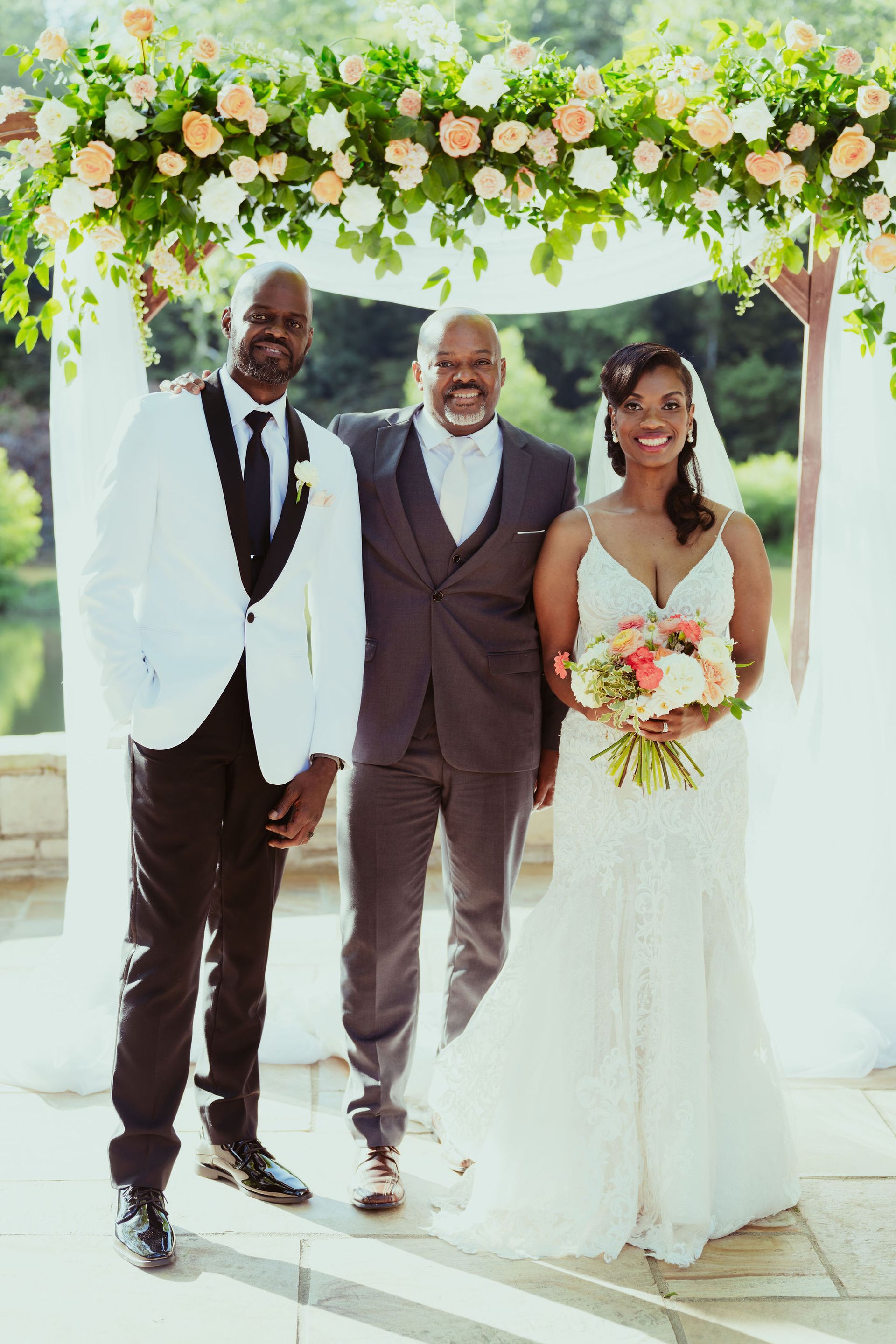 A bride and groom are posing for a picture with a man in a suit.