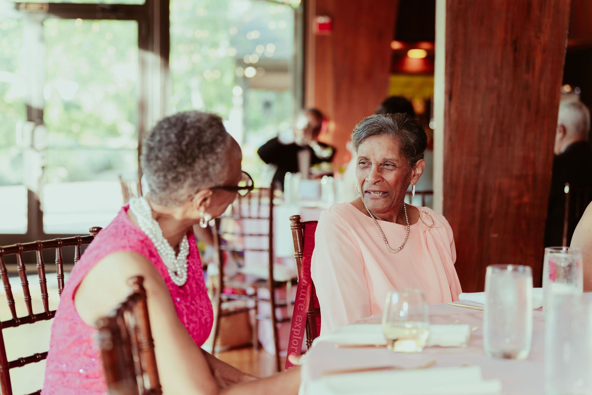 Two women are sitting at a table in a restaurant talking to each other.