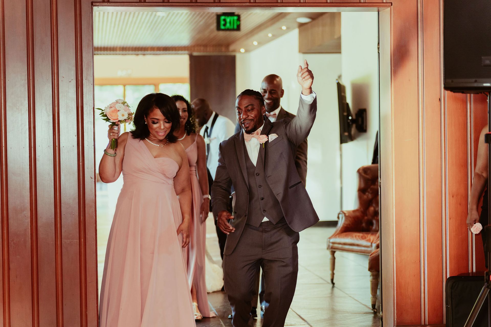 A bride and groom are walking through a doorway with their wedding party.