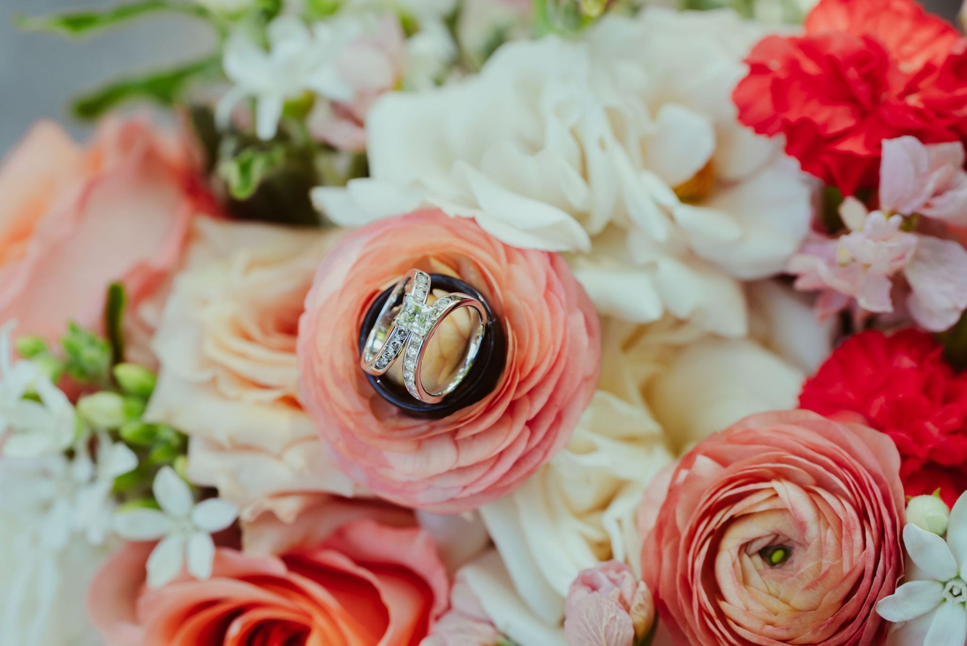 The wedding rings are sitting on top of a bouquet of flowers.