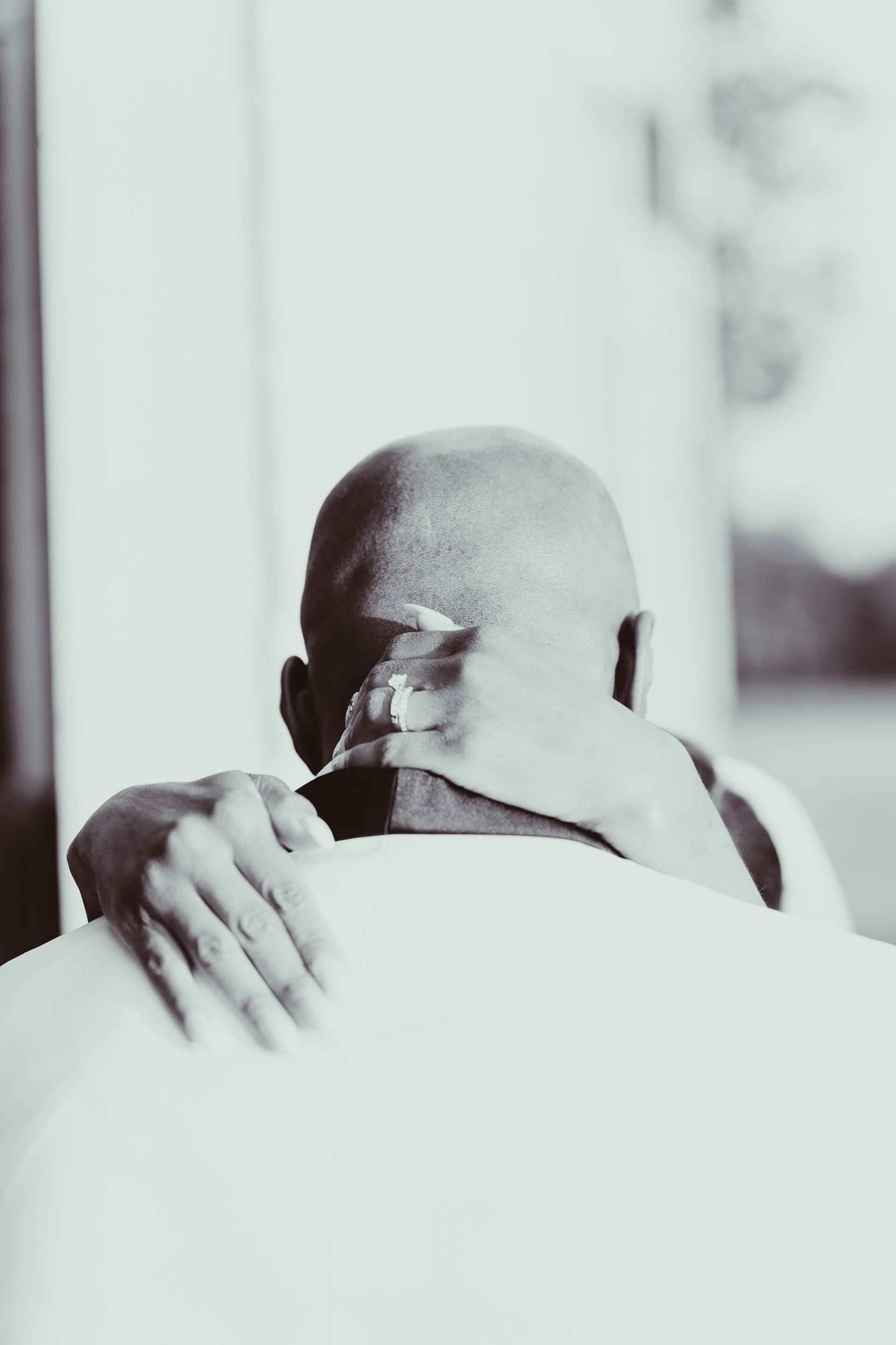 A man with a ring on his finger is hugging another man.