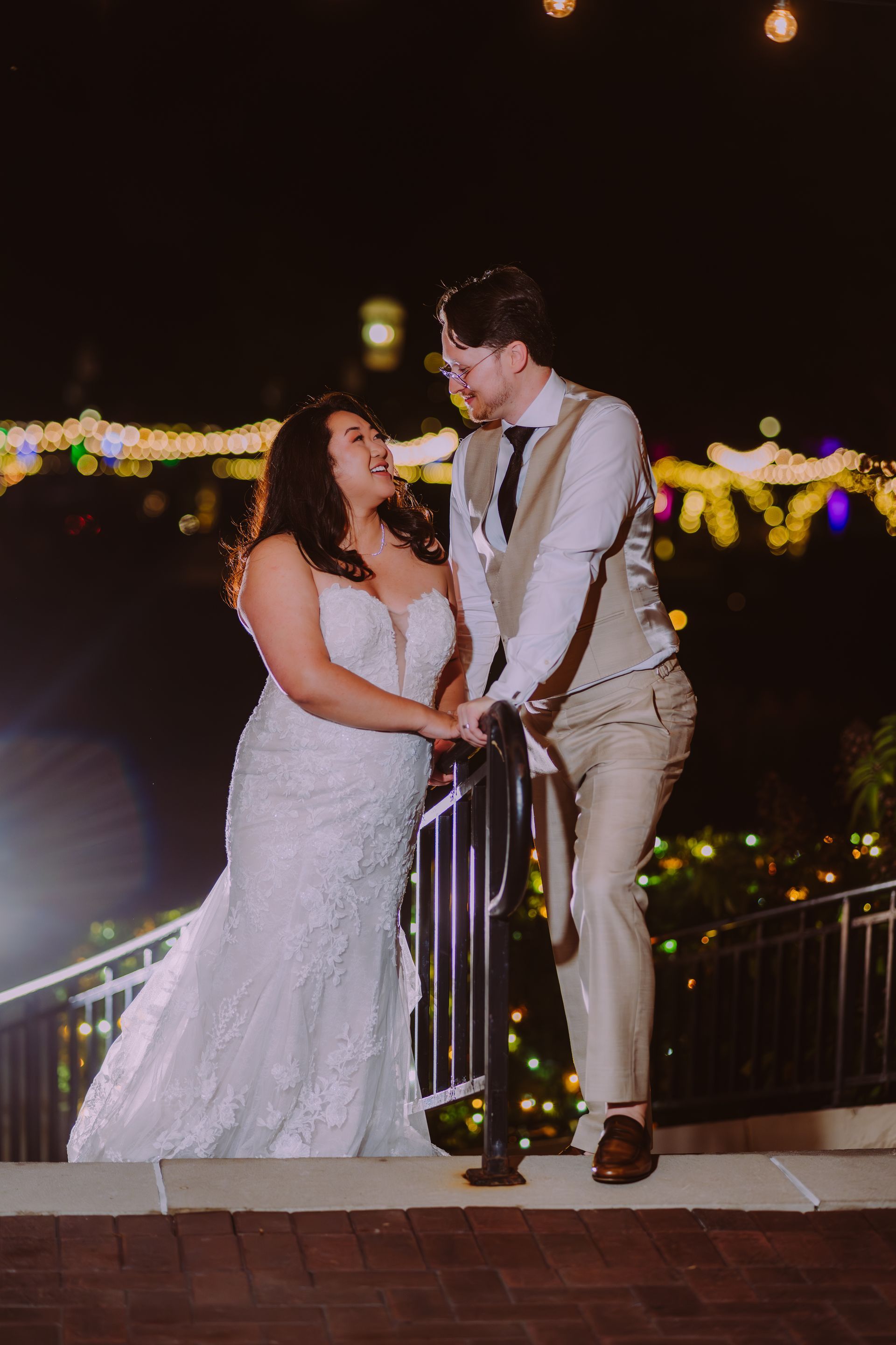 Bride and groom gaze at each other at night, lit by string lights.  at franklin park conservatory