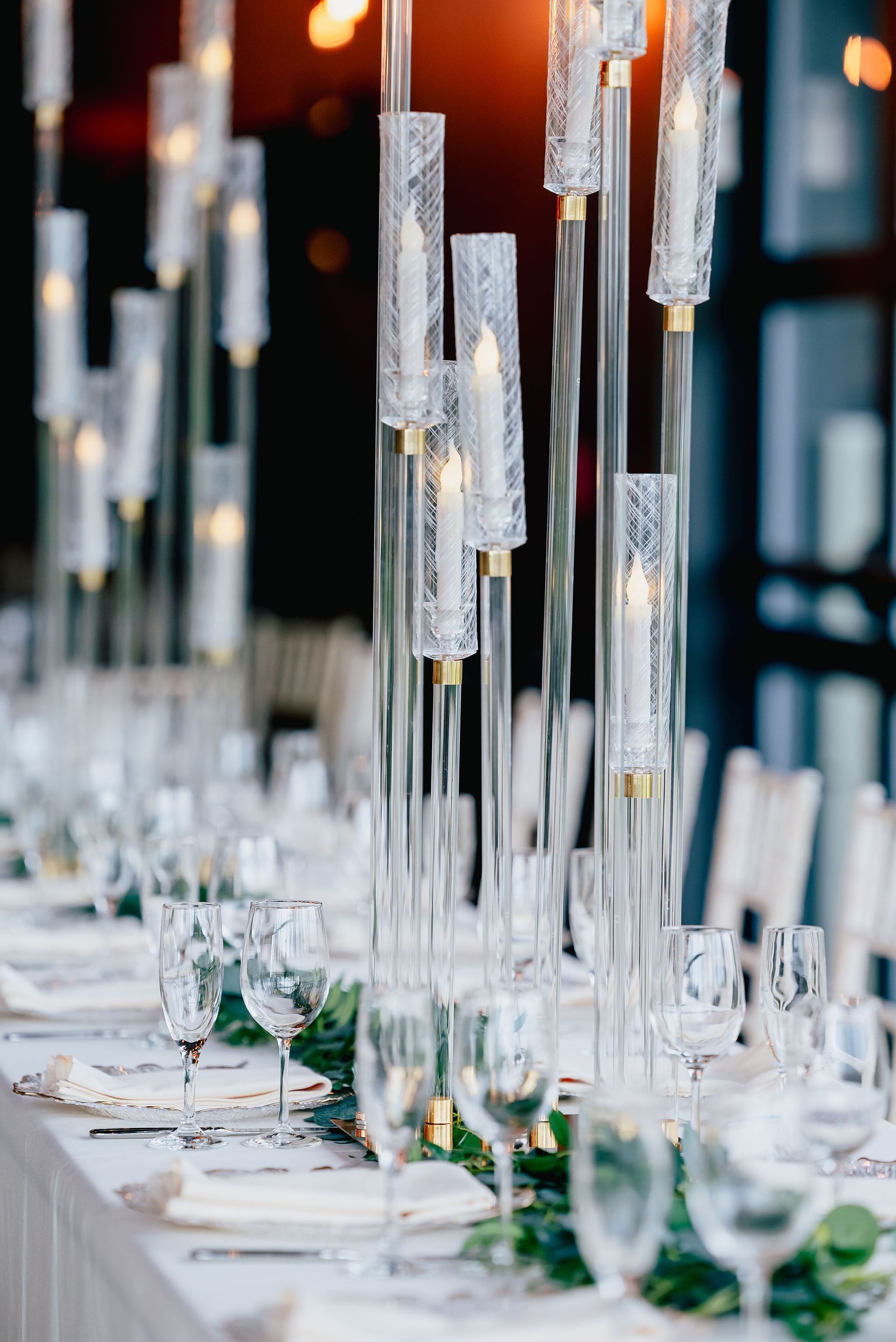 A long table with a lot of candles and glasses on it.