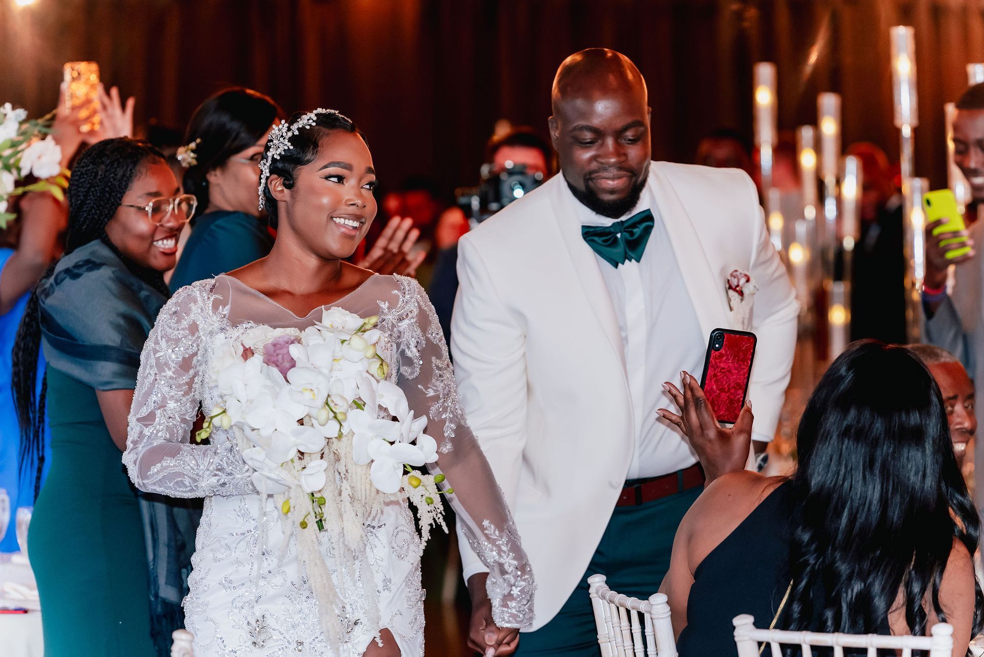 A bride and groom are walking down the aisle at their wedding reception holding hands.
