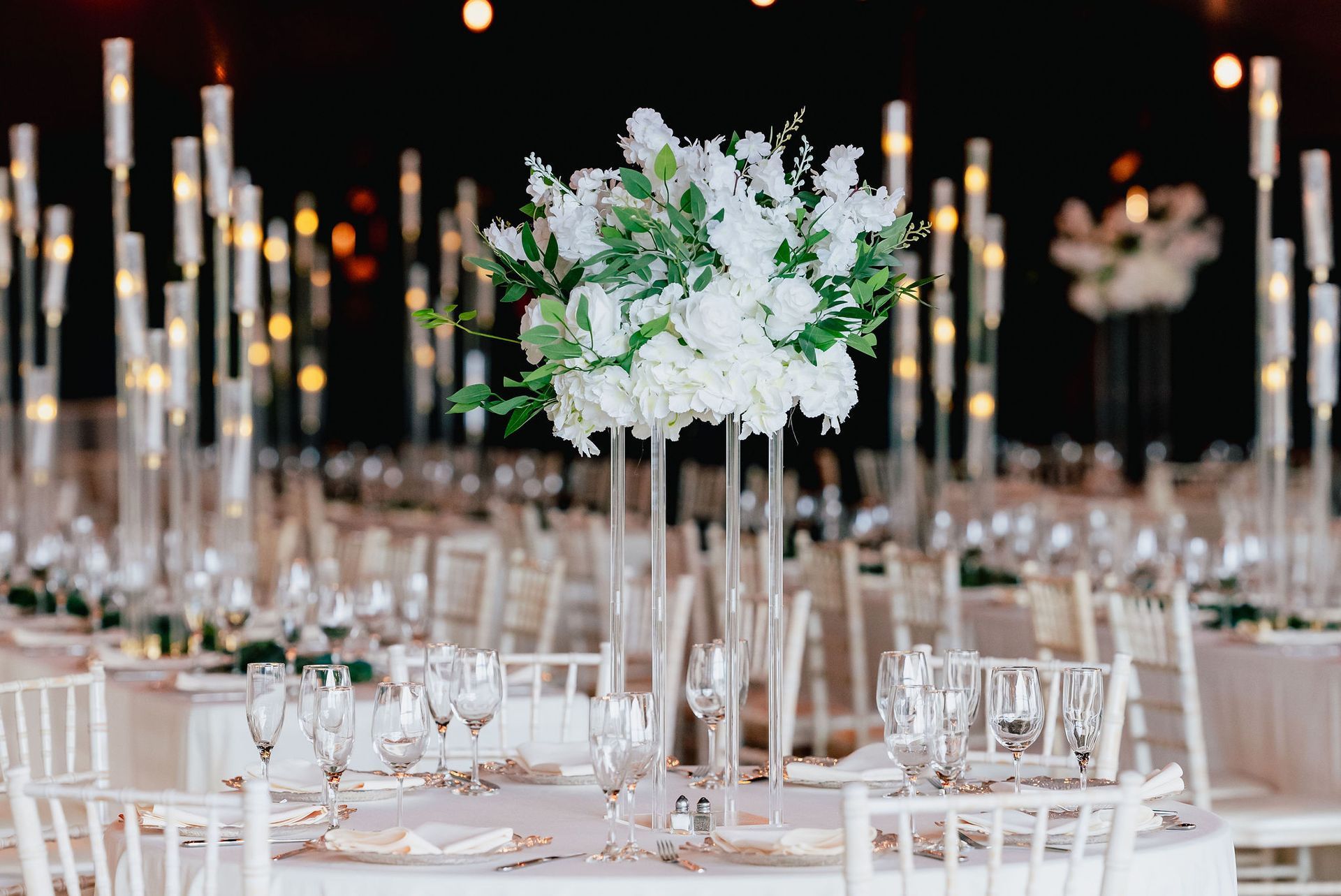 A table set for a wedding reception with a vase of flowers on it.