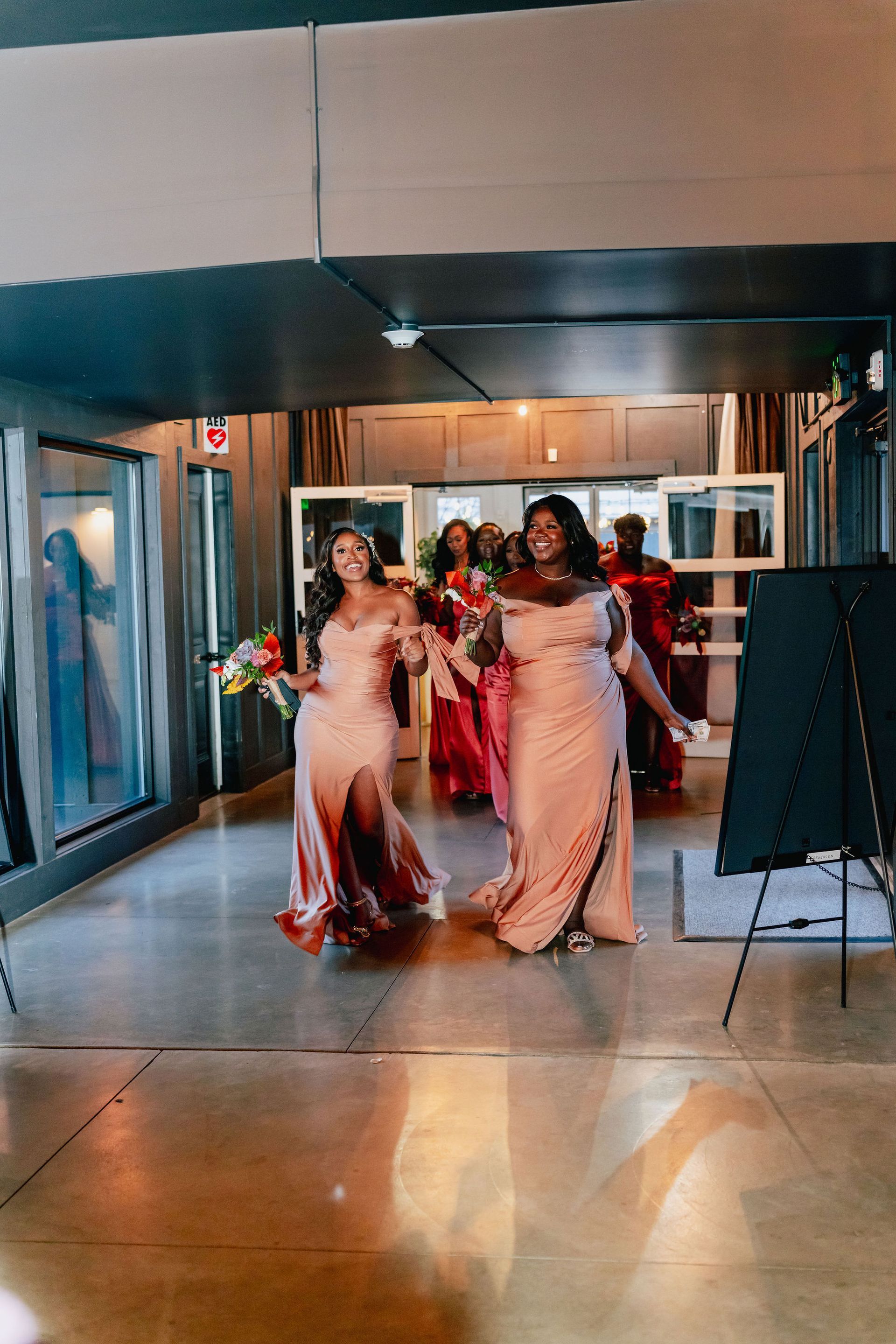A group of women in long dresses are walking through a hallway.