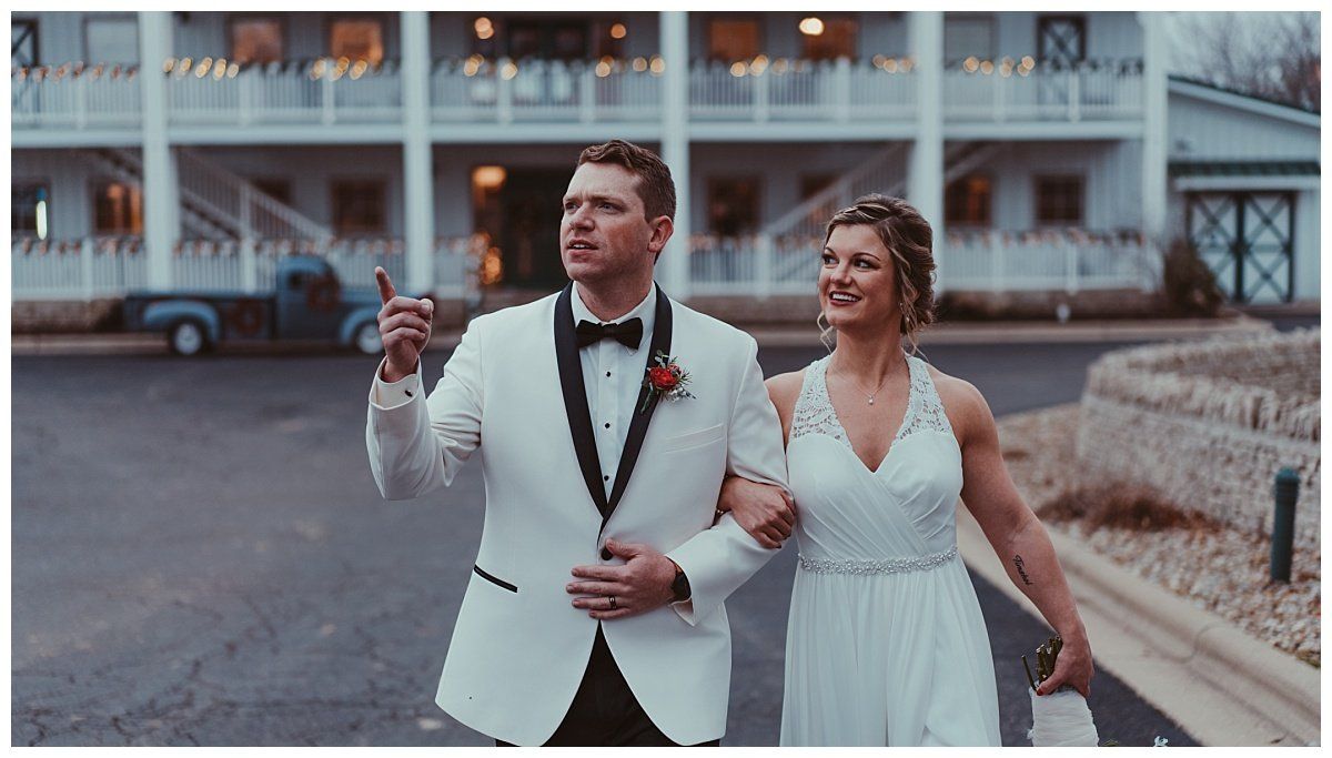 a bride and groom are walking down the street holding hands .