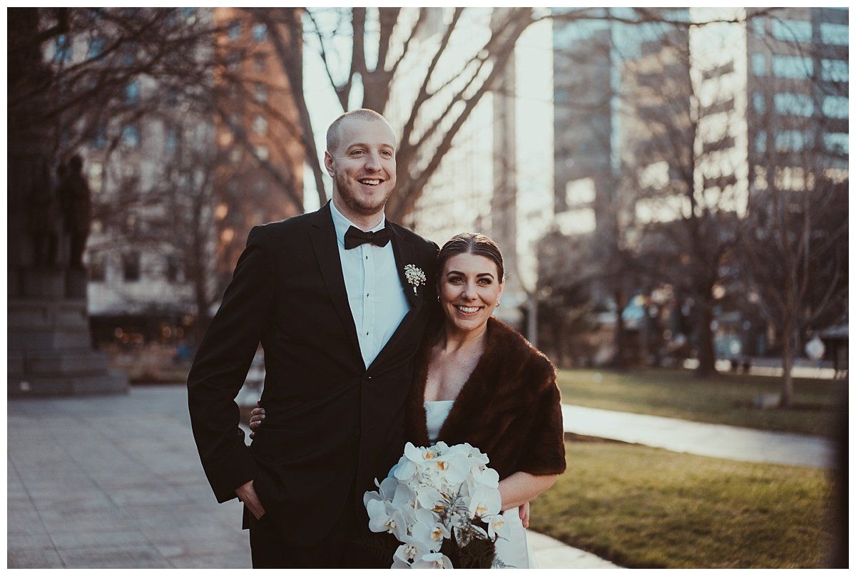 a bride and groom are posing for a picture in a park .