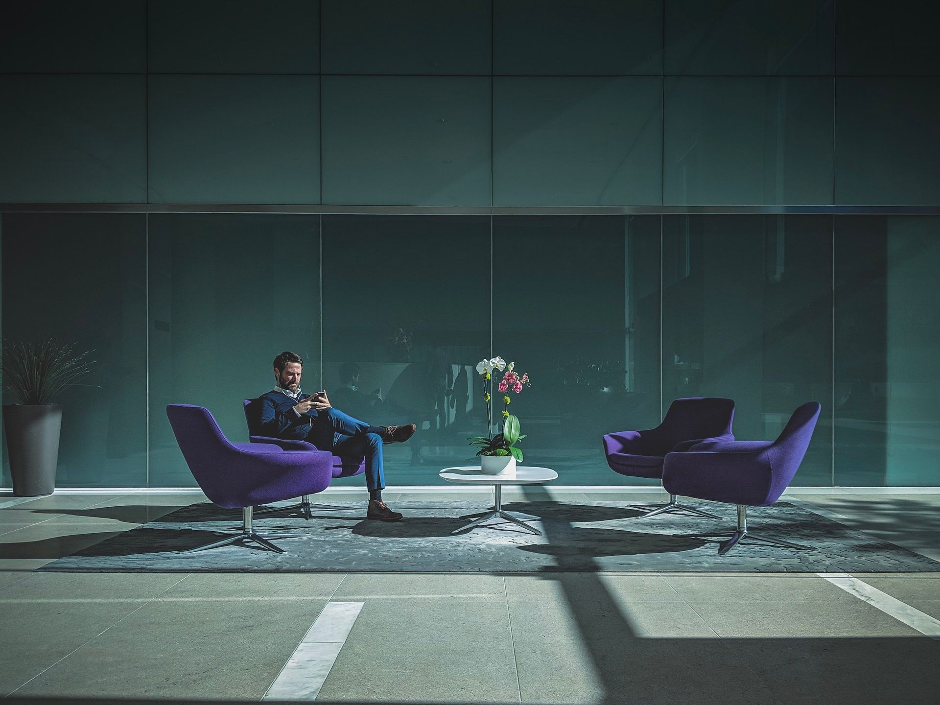 a man is sitting in a chair in front of a glass wall .