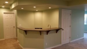 Corner bar area with light green walls, a brown countertop, and two white doors.