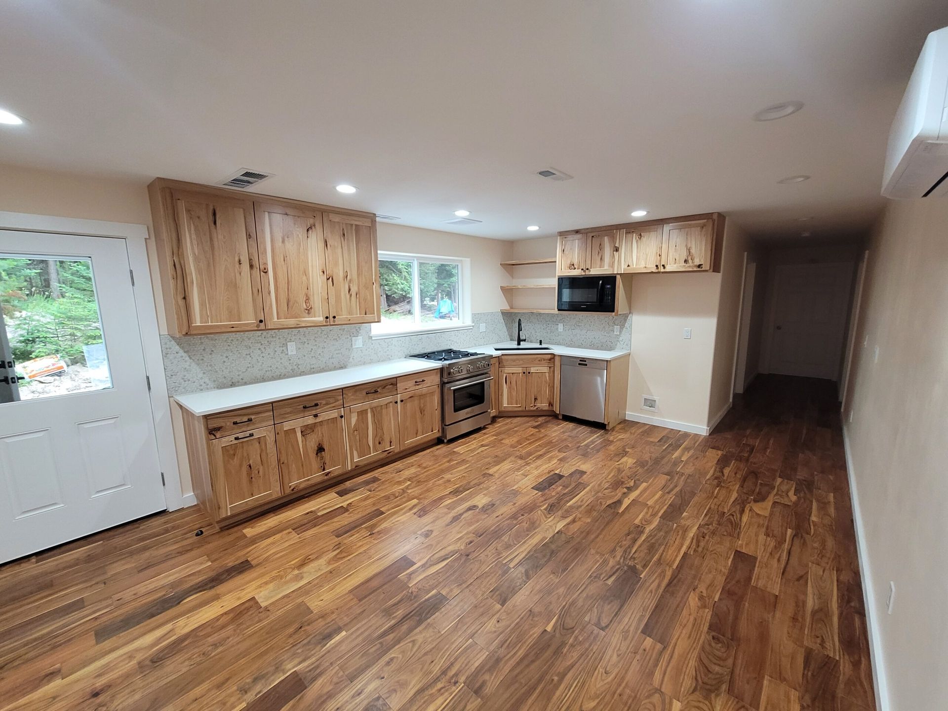 Kitchen with light wood cabinets, stainless steel appliances, and hardwood floors.