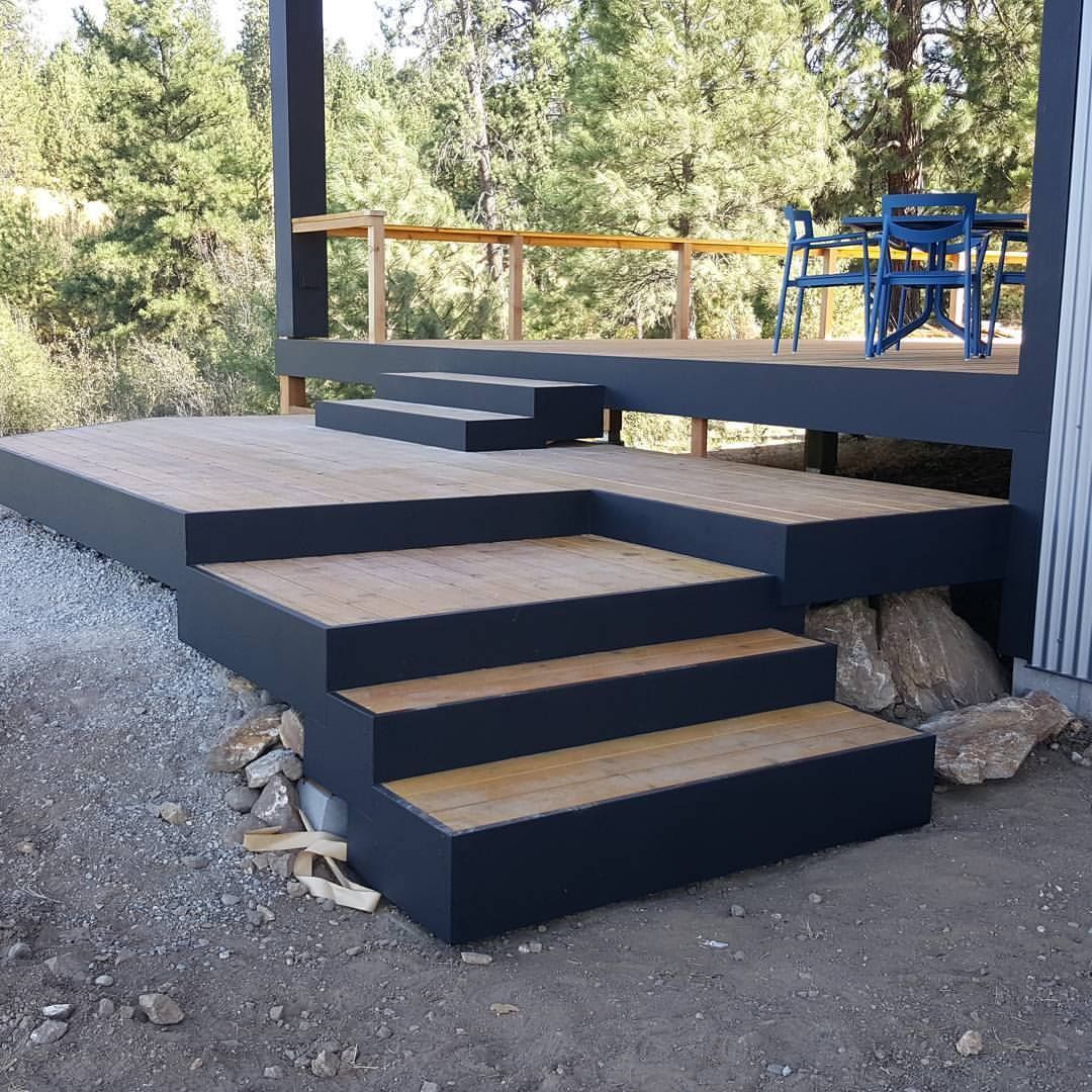 Outdoor deck with gray painted frame, wooden steps, and a blue table and chairs.
