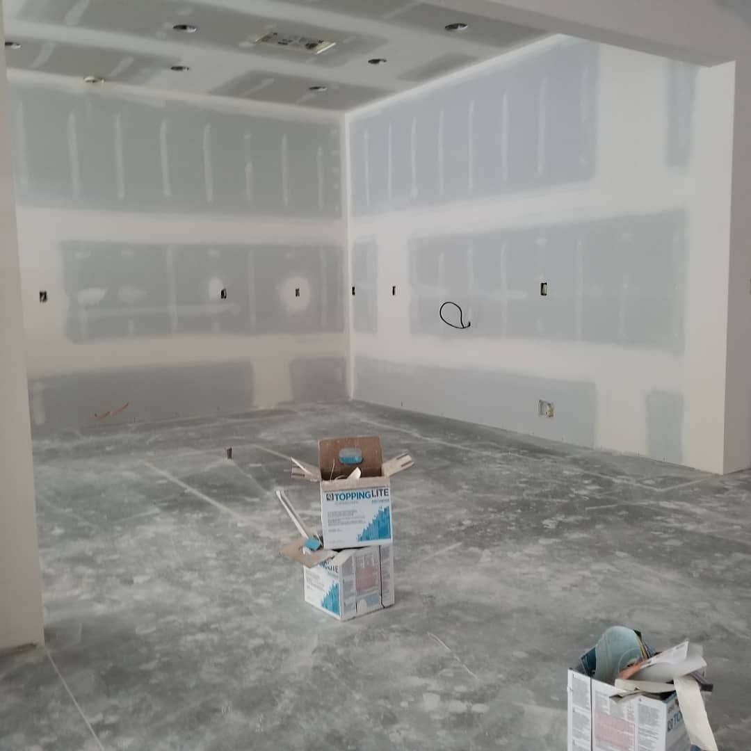 Interior room under construction with drywall installed and boxes on the concrete floor.