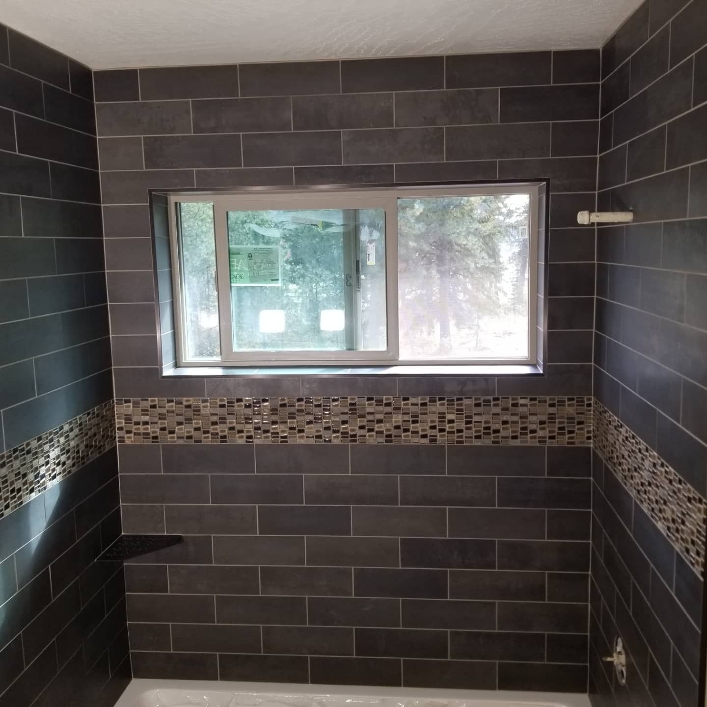 Bathroom with dark gray subway tile walls and a decorative mosaic border.