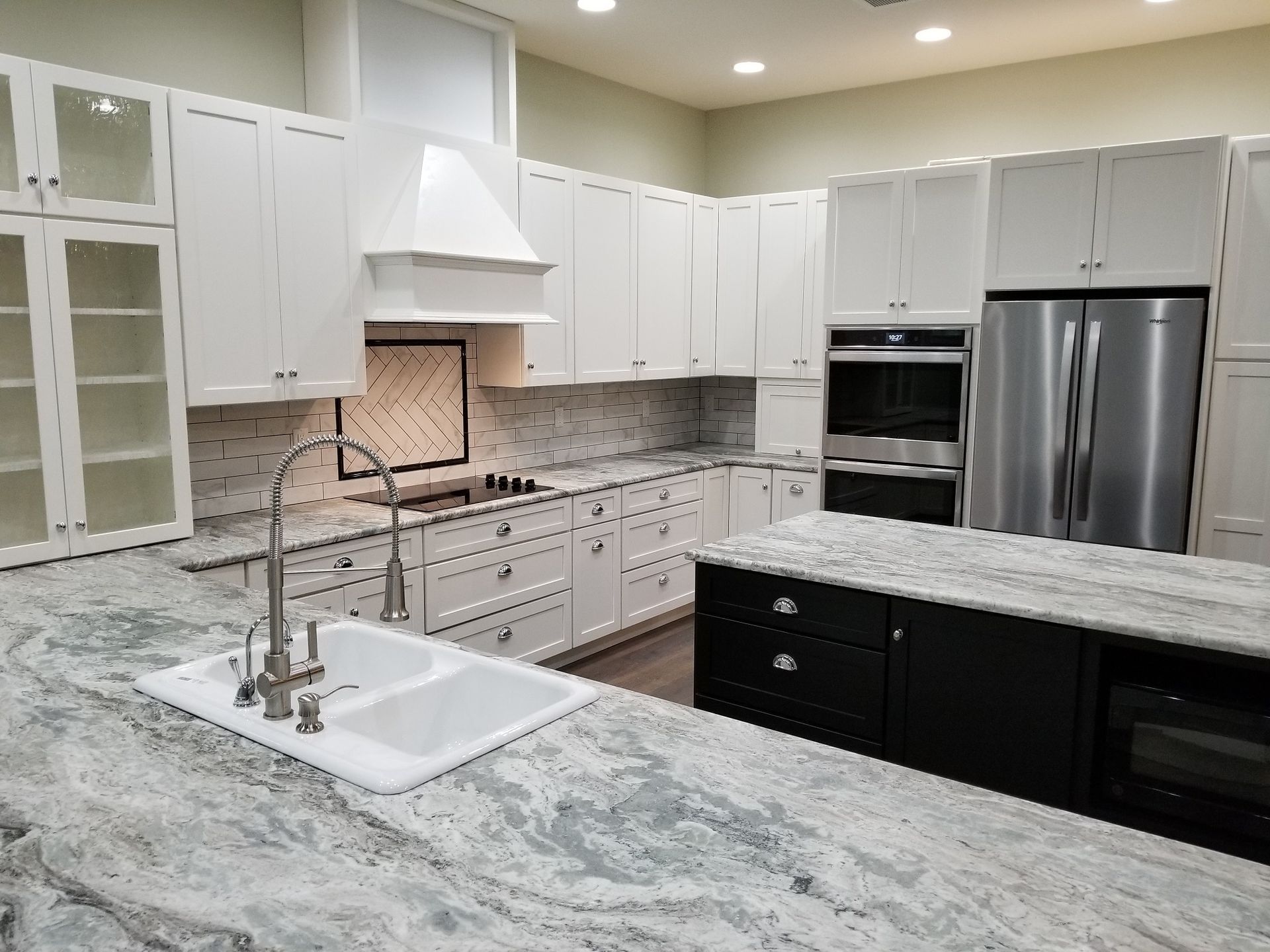 Modern kitchen with white cabinets, stainless steel appliances, and a gray countertop island.