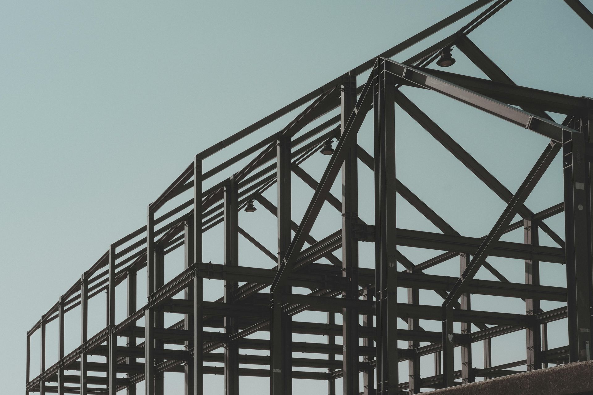 Wooden staircase under construction, with metal spindles. A-frame ladder visible.