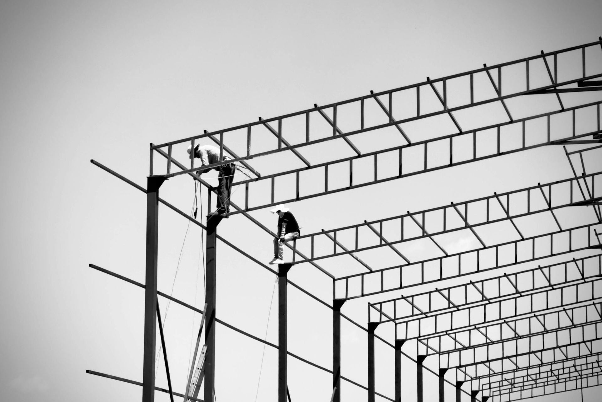 Wooden staircase under construction, with metal spindles. A-frame ladder visible.