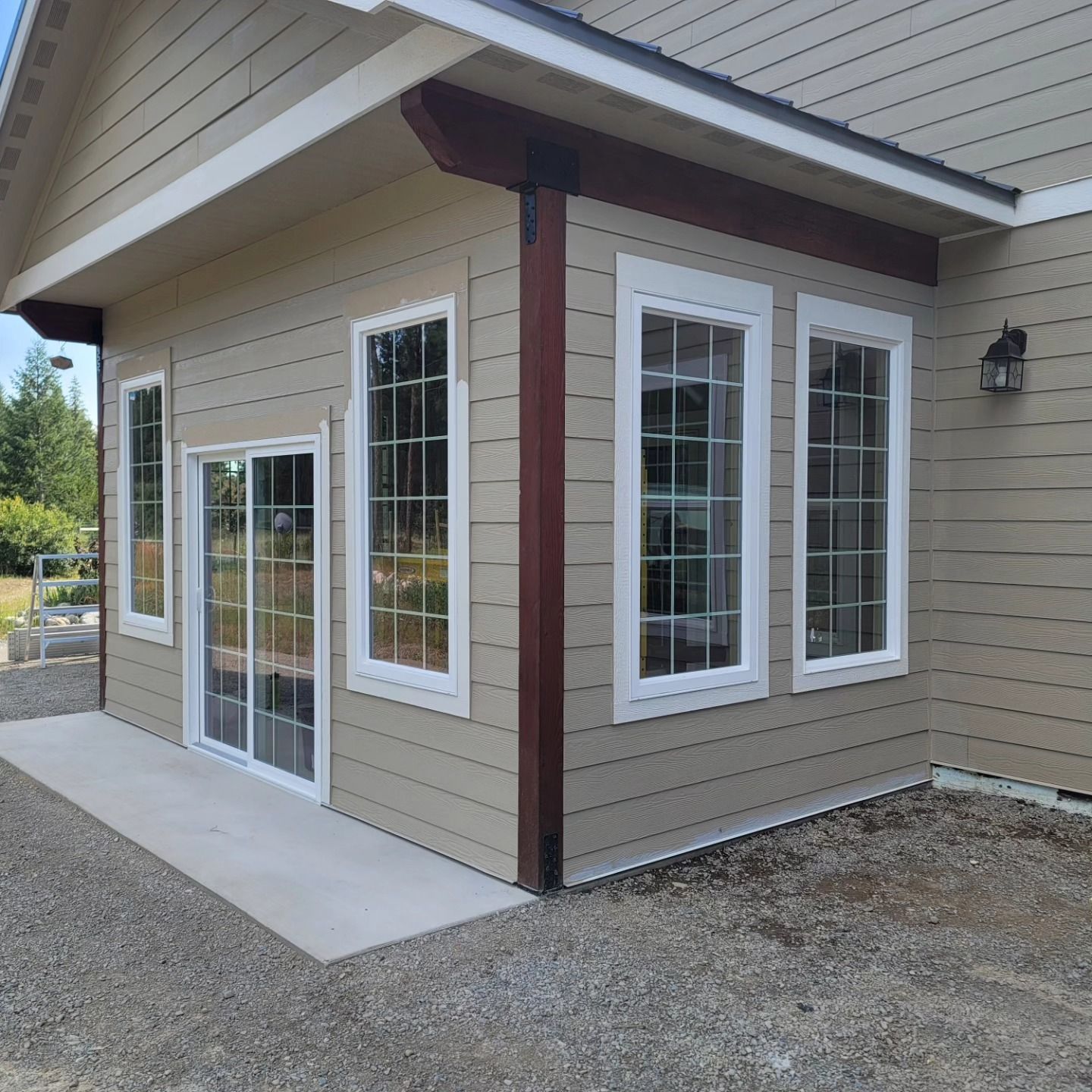 Beige building with white-framed windows, sliding glass door, and a concrete patio.