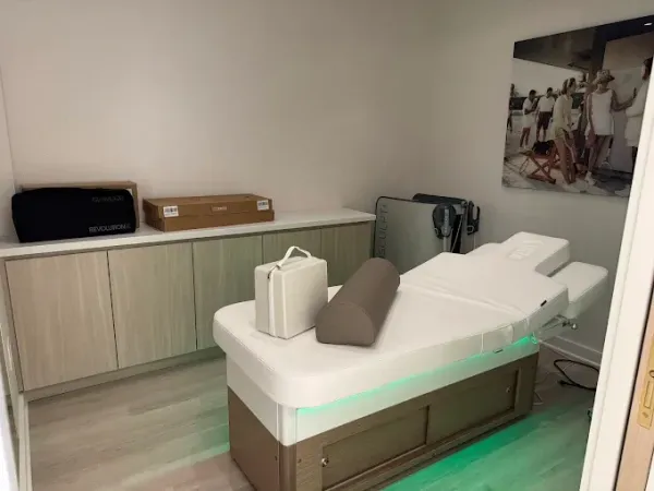 Massage therapy room with massage table, cabinets, and a framed photo.