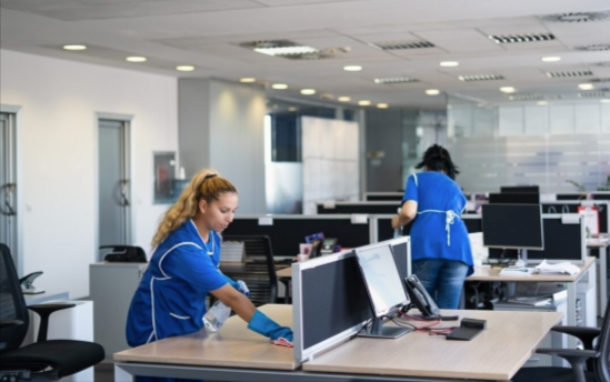 Man in mask and gloves disinfecting a dental office countertop.