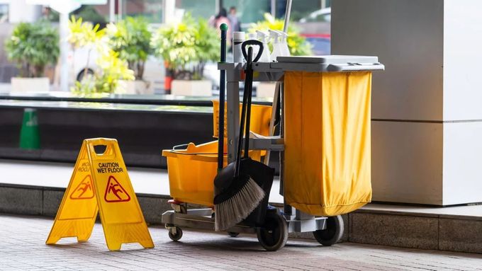 Yellow cleaning cart with supplies next to 