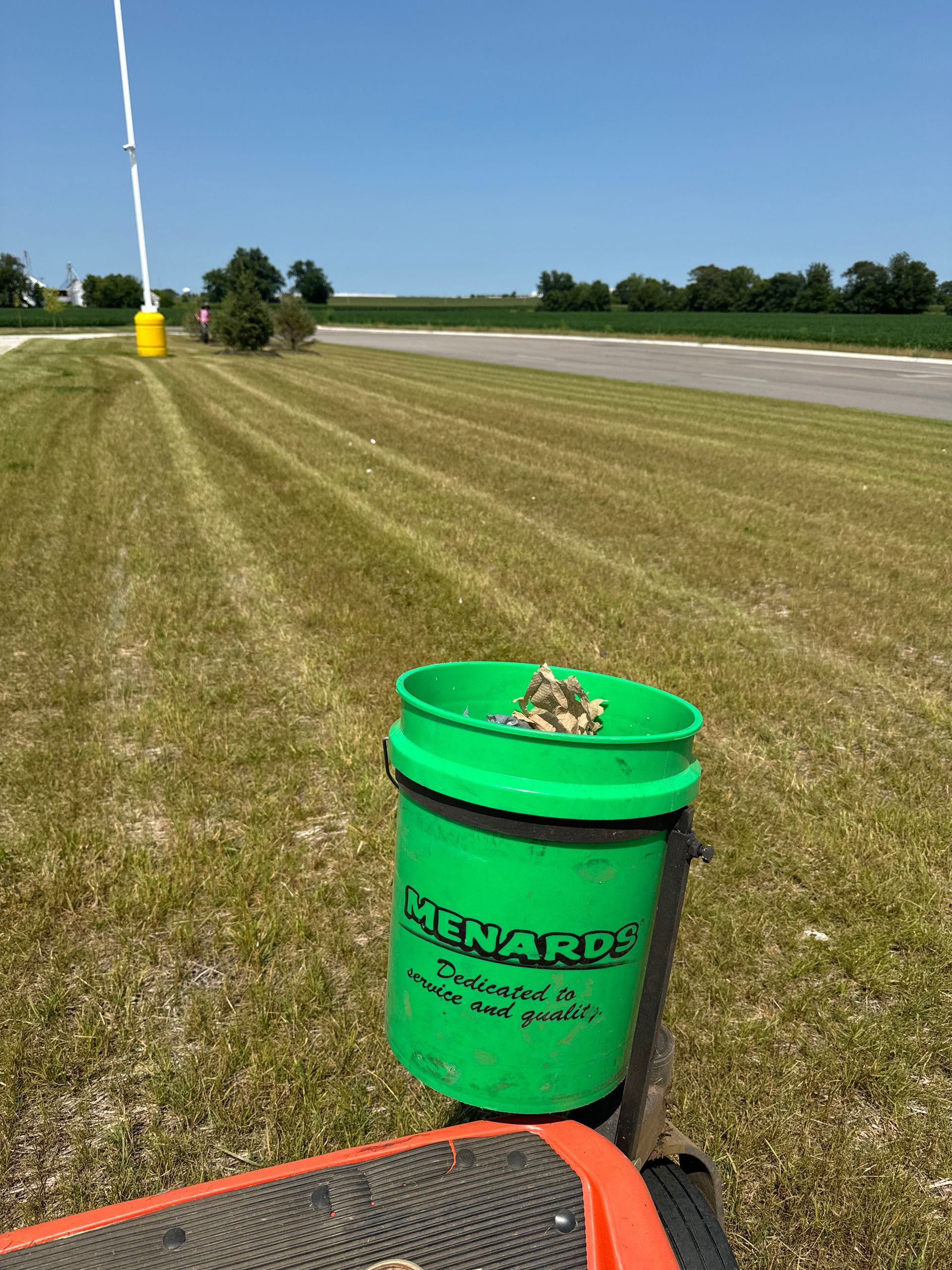 A green bucket is sitting on top of a lawn mower.
