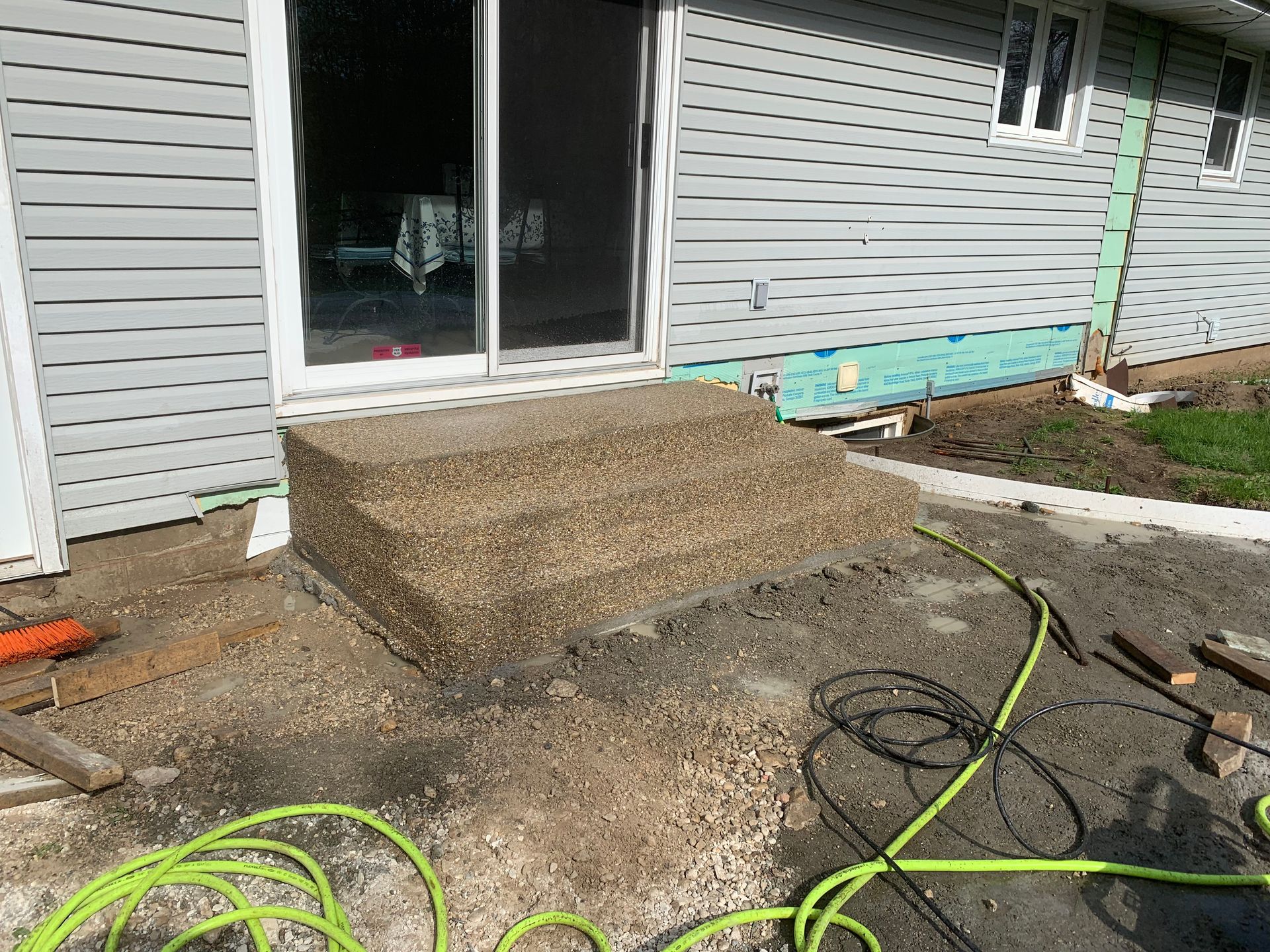 A hose is sitting on the ground in front of a house.