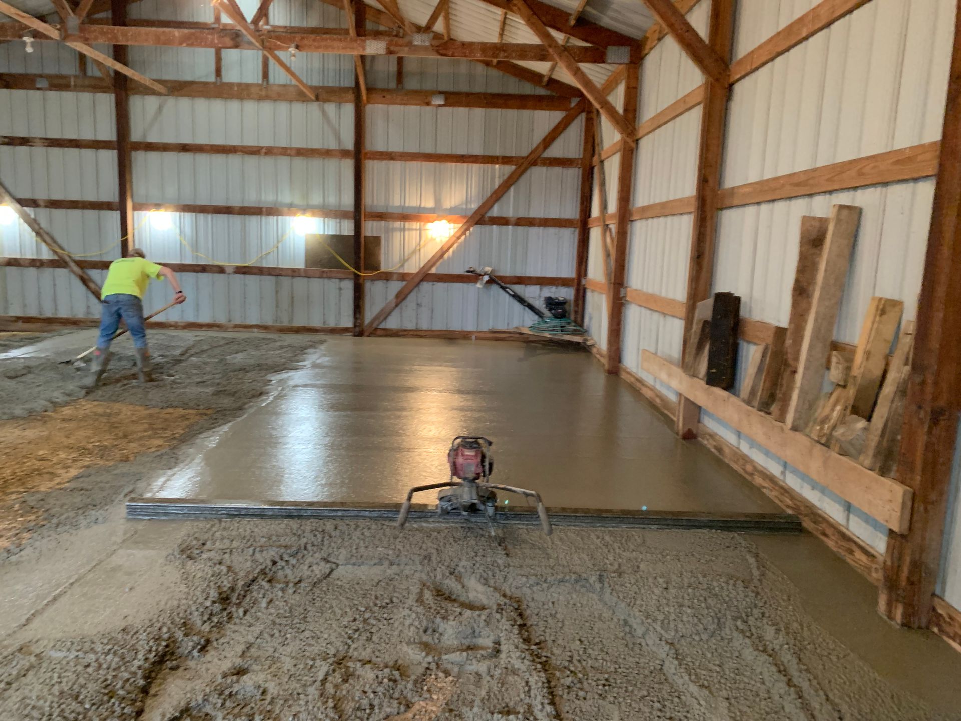 A man is working on a concrete floor in a barn.