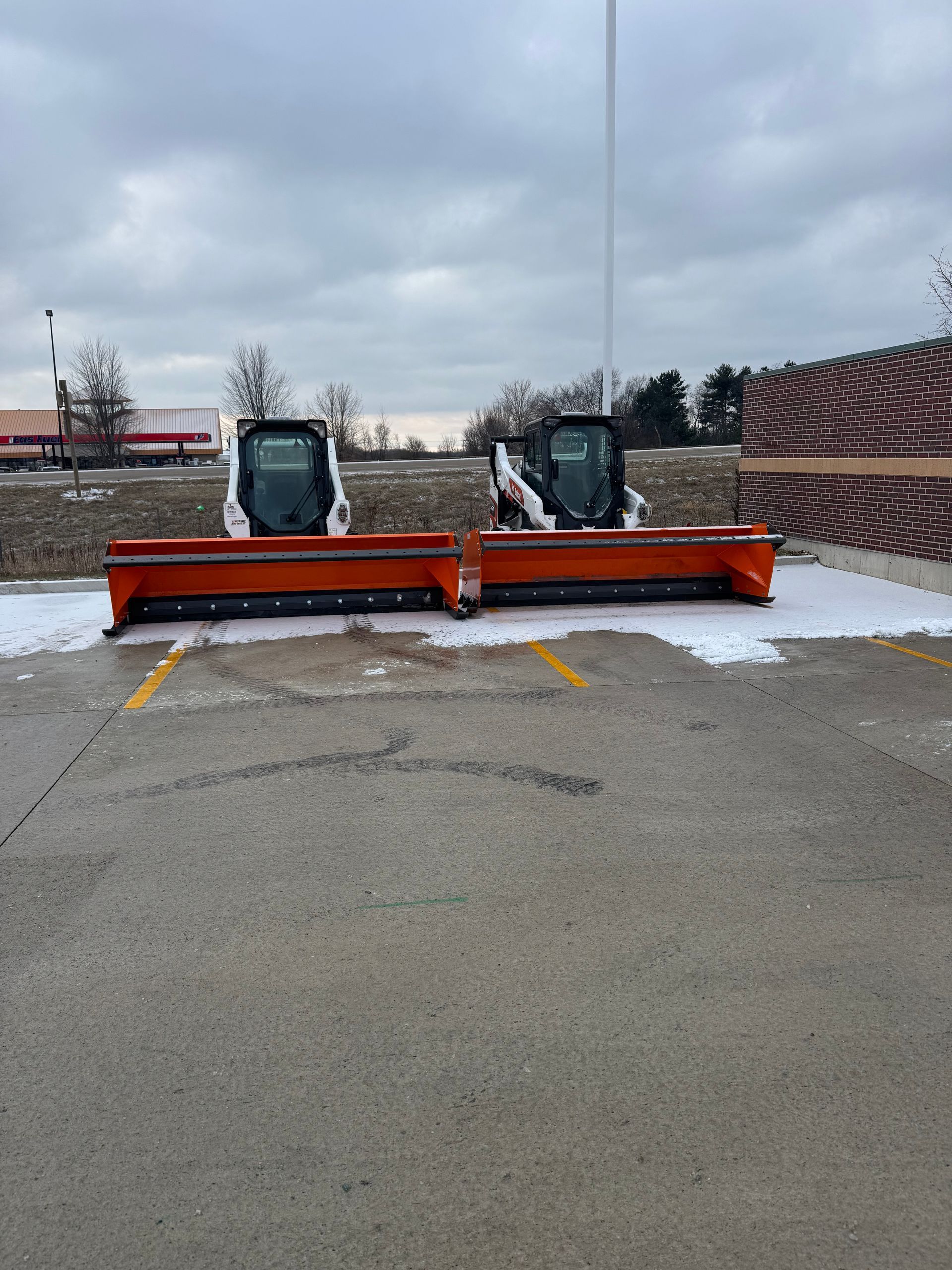 Two snow plows are parked in a parking lot