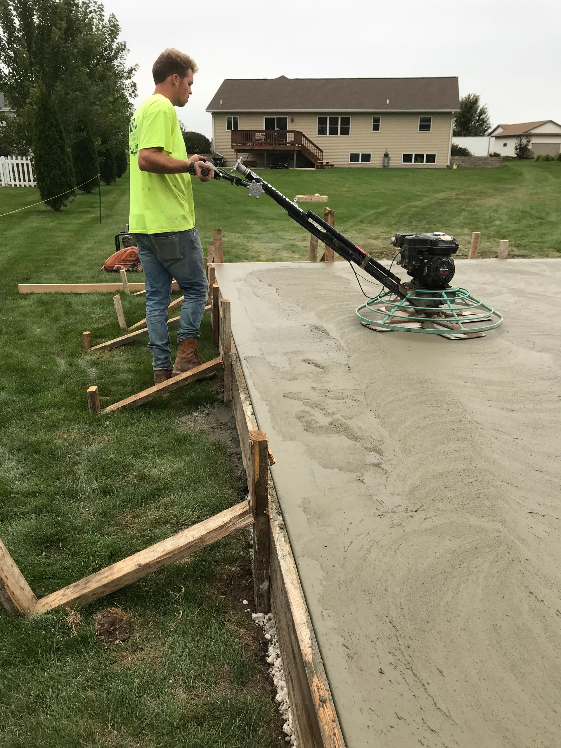 A man is using a machine to finish a concrete slab.