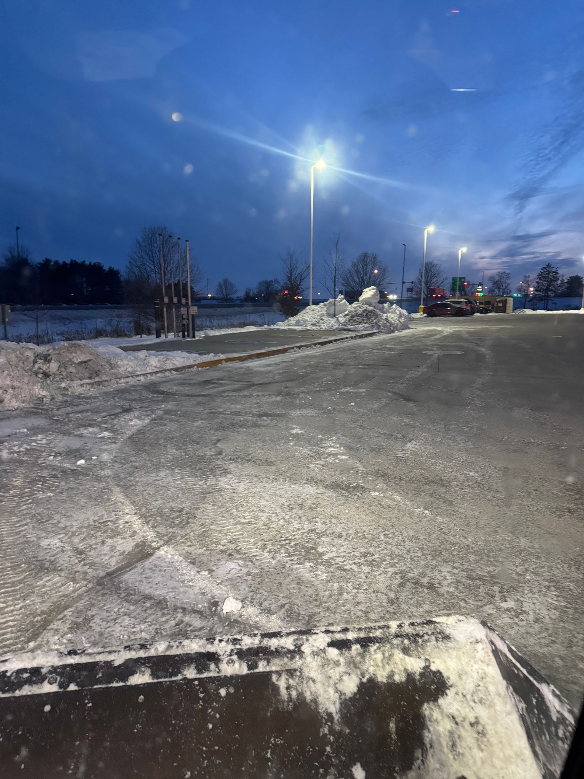 A car is driving down a snowy road at night.