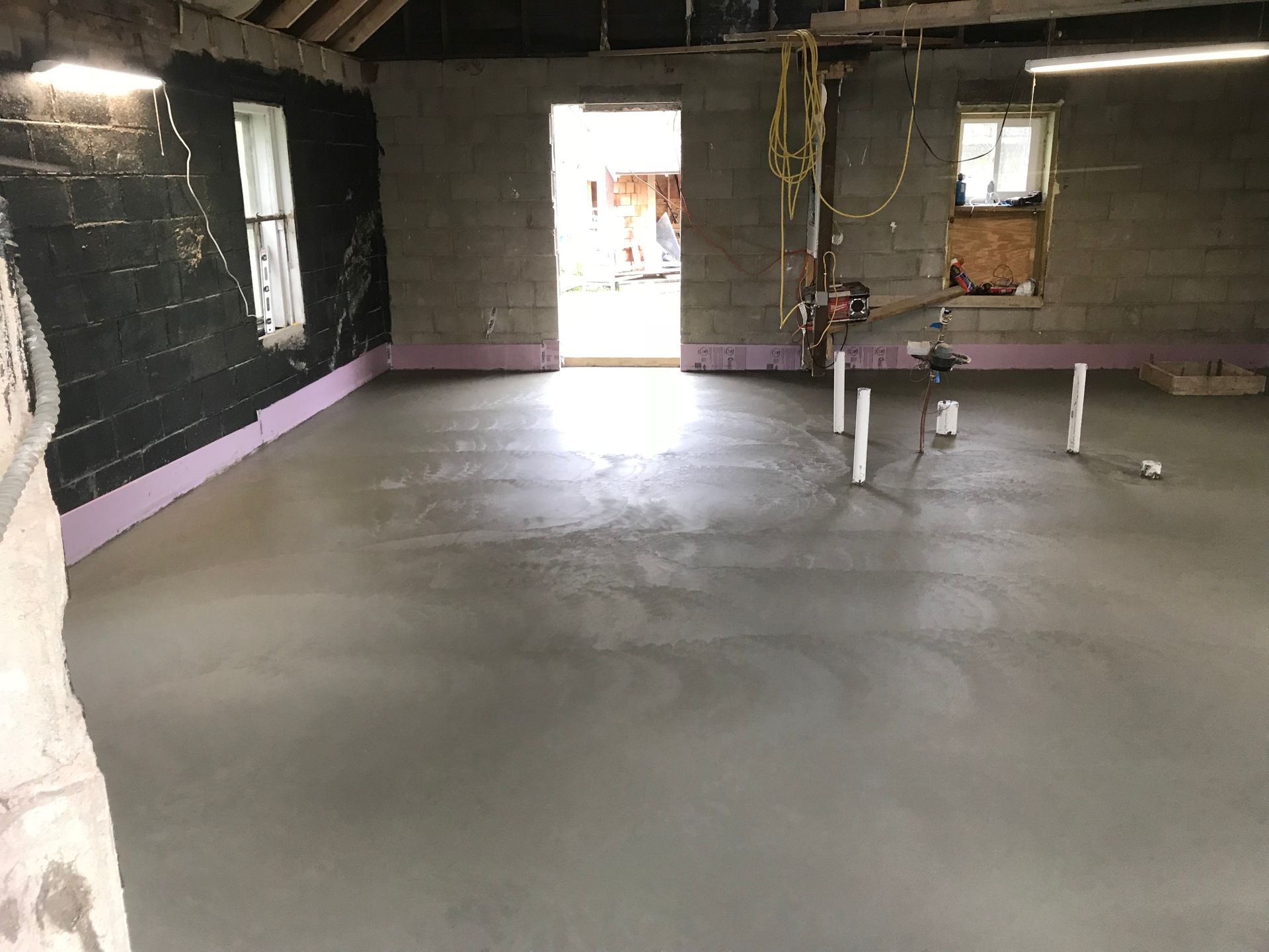 A room with a concrete floor and a brick wall.