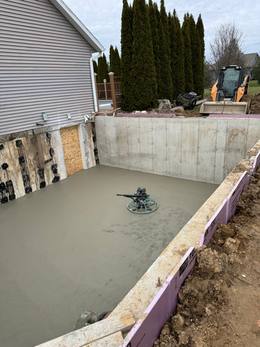 A concrete floor is being poured in front of a house.