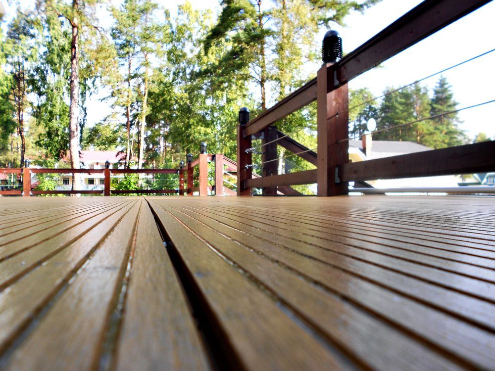 Wooden deck with cable railing, trees in background.