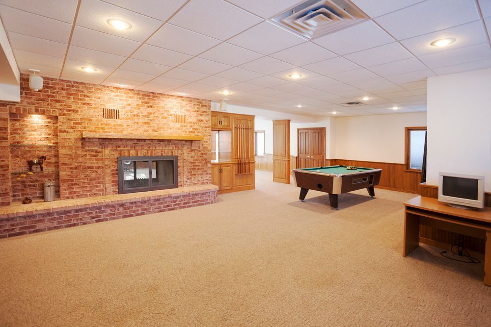 Spacious finished basement with fireplace, pool table, and a computer desk; tan carpet.
