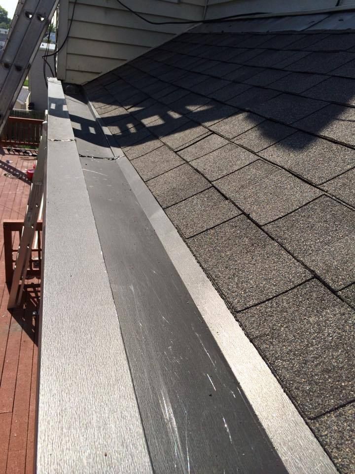 A gutter and roof edge with gray shingles and a ladder.