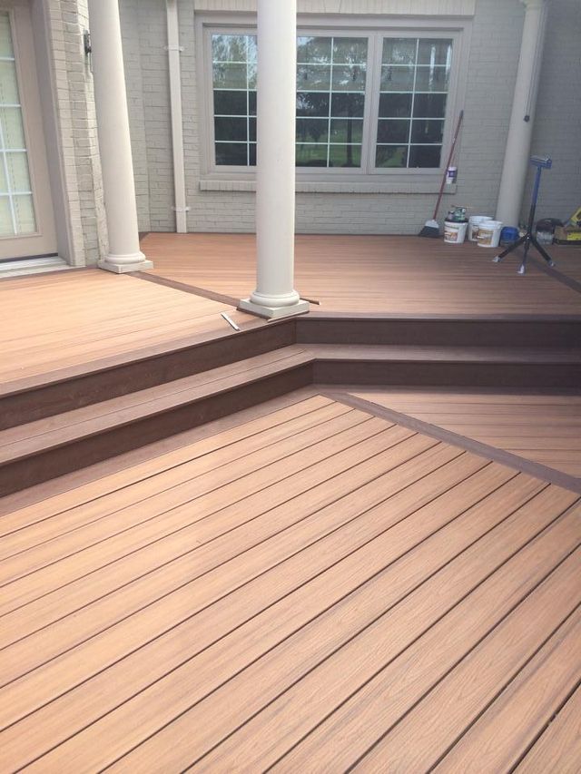 Composite deck with steps leading to a higher level, brown and tan tones, near a white pillar and house.