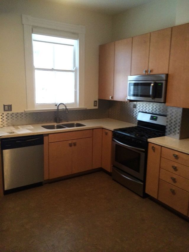 Kitchen with light wood cabinets, stainless steel appliances, and a window.