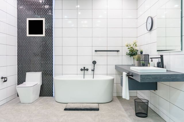Modern bathroom with white tile, soaking tub, floating vanity, and black accents.