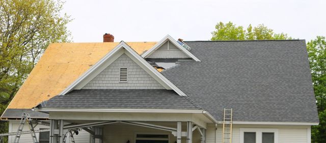 House with a roof partially covered with shingles, partially with exposed wood, and a ladder leaning against it.